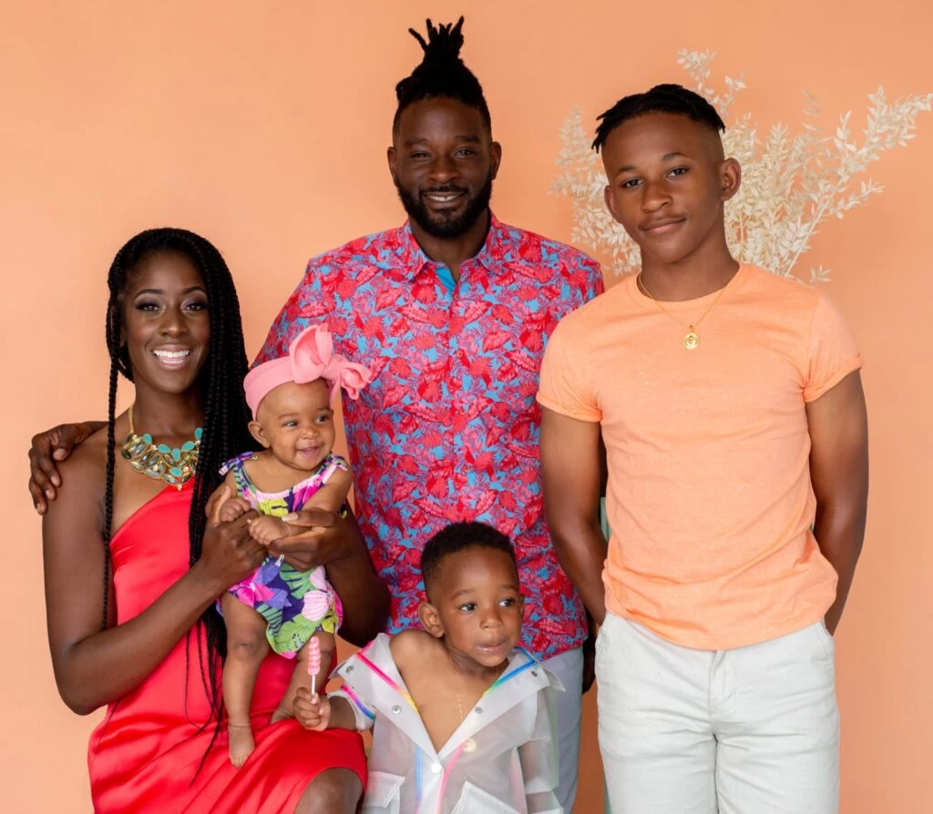 A family posing for a photo in front of an orange wall.